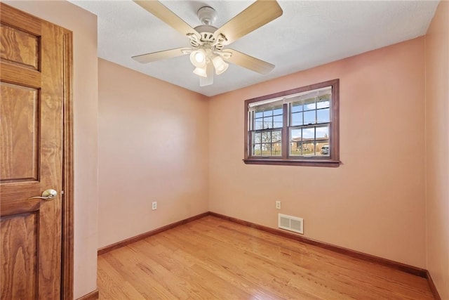 empty room featuring a ceiling fan, baseboards, visible vents, and light wood finished floors