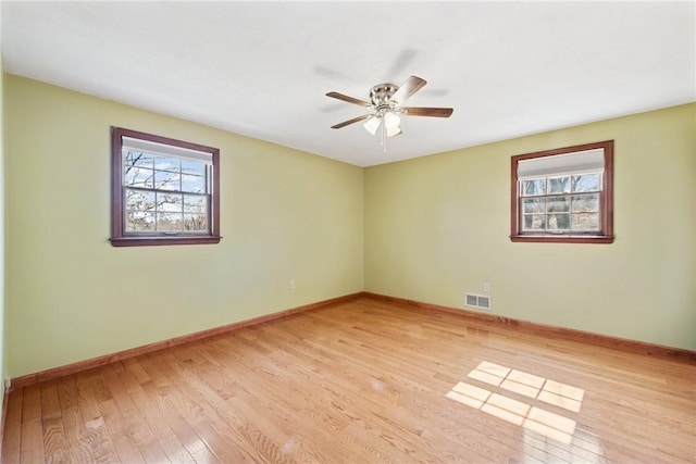 unfurnished room featuring a ceiling fan, light wood-style flooring, baseboards, and visible vents