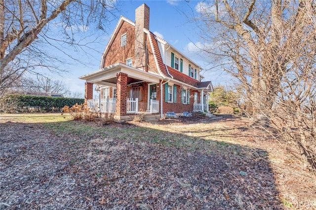 view of front of home featuring brick siding, a porch, and a chimney