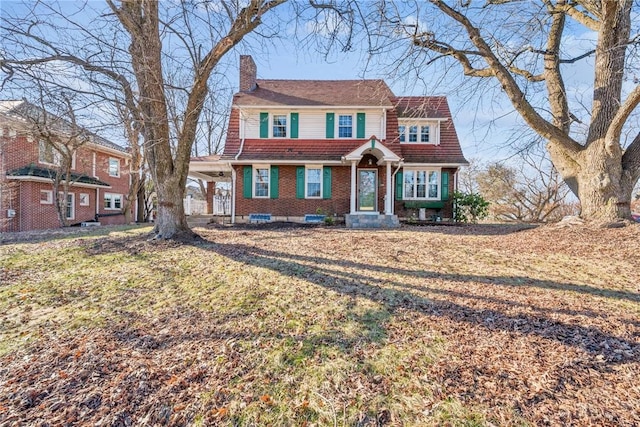 view of front of property with a front lawn, brick siding, and a chimney