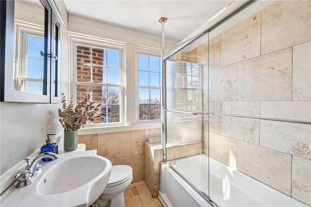 full bath with plenty of natural light, tile walls, and a sink