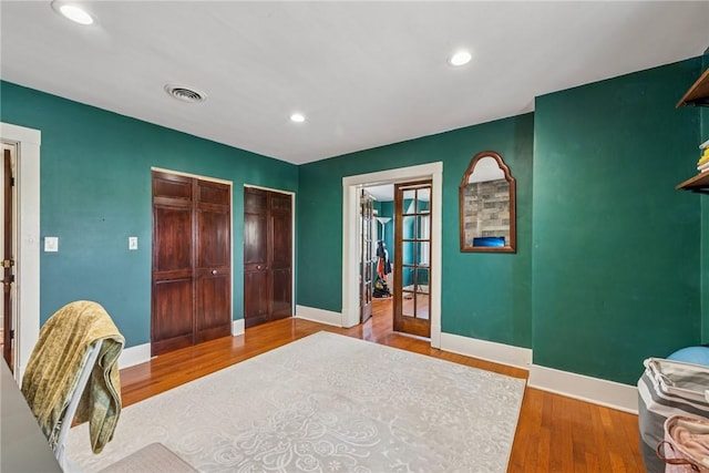 bedroom with visible vents, multiple closets, wood finished floors, recessed lighting, and baseboards