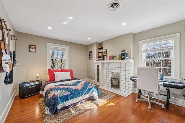 bedroom with visible vents, baseboards, recessed lighting, a fireplace, and wood-type flooring