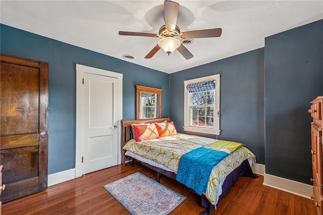 bedroom featuring visible vents, a ceiling fan, baseboards, and hardwood / wood-style flooring