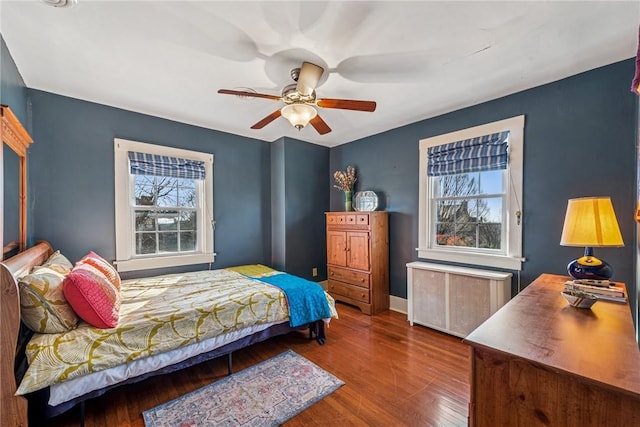 bedroom featuring radiator, baseboards, a ceiling fan, and wood finished floors