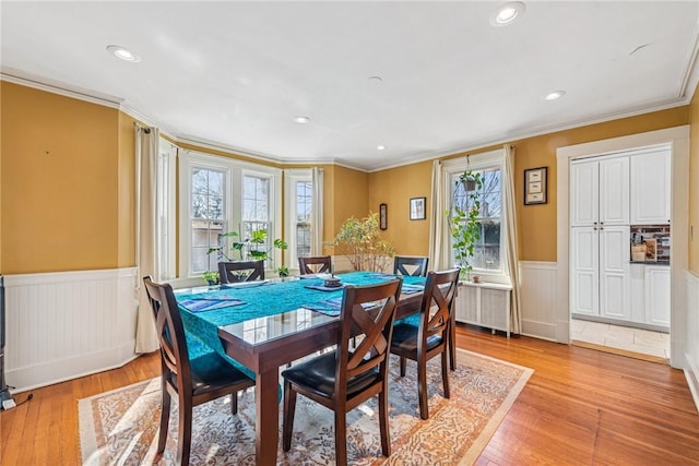 dining room with recessed lighting, a wainscoted wall, light wood-style flooring, and ornamental molding