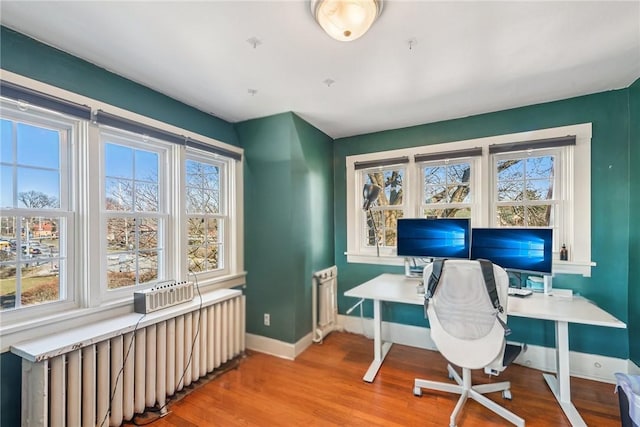 office with light wood-type flooring, baseboards, radiator, and radiator heating unit