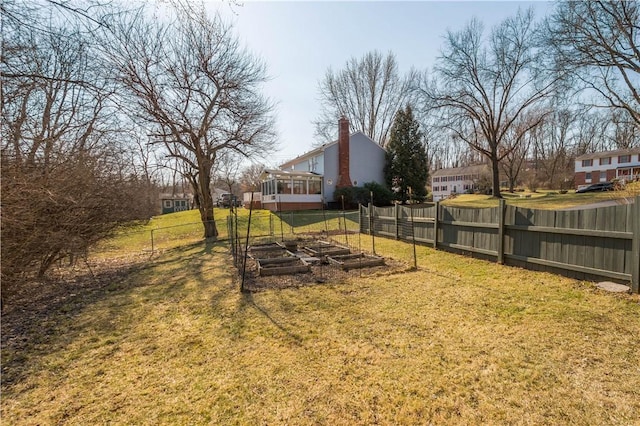 view of yard with a vegetable garden, fence, and a sunroom