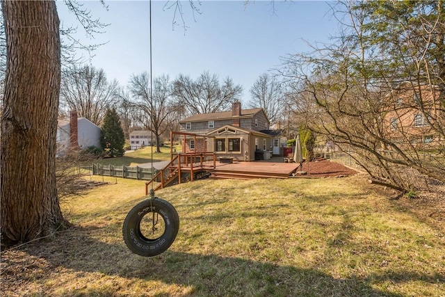 rear view of house featuring a chimney, a wooden deck, a yard, and fence