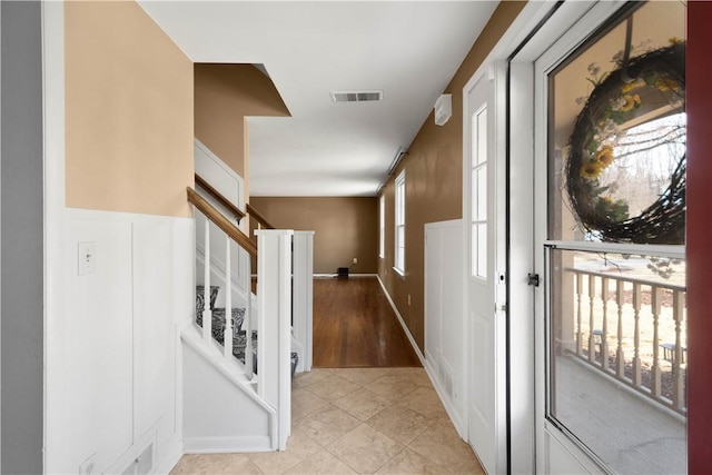 entryway featuring light tile patterned floors, visible vents, and stairs