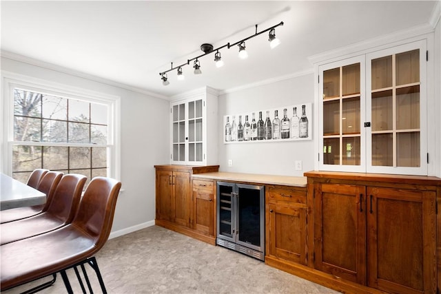 bar featuring crown molding, a dry bar, beverage cooler, and baseboards