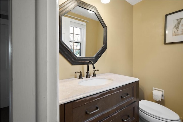 half bathroom featuring vanity and toilet