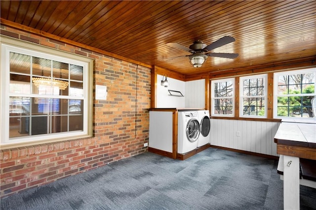 washroom with brick wall, washing machine and dryer, wooden ceiling, a ceiling fan, and dark colored carpet