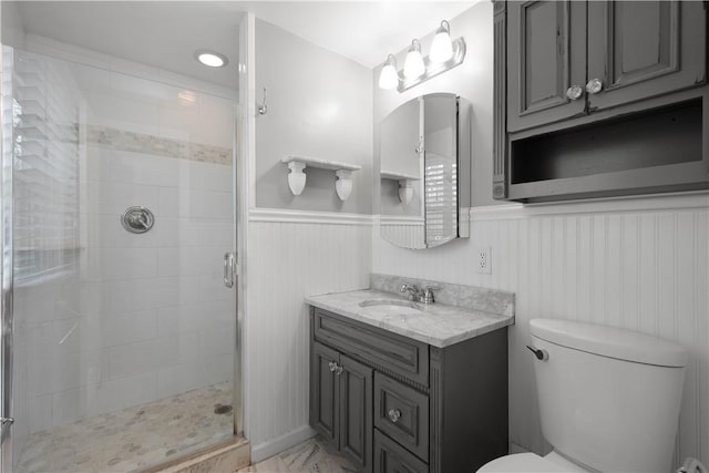 bathroom with a wainscoted wall, a stall shower, toilet, and vanity