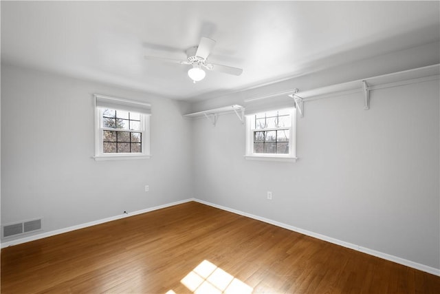 spare room featuring plenty of natural light, wood finished floors, visible vents, and baseboards