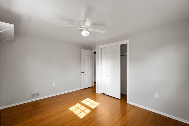 unfurnished bedroom featuring visible vents, baseboards, a closet, and wood finished floors