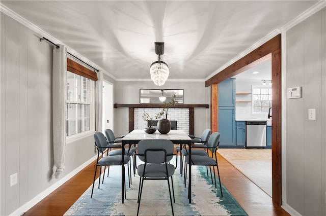 dining space with an inviting chandelier, light wood-style flooring, crown molding, and baseboards