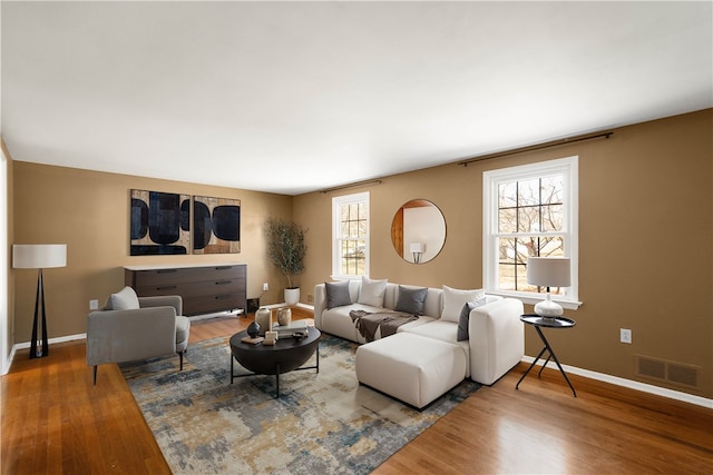 living area with visible vents, baseboards, and wood finished floors