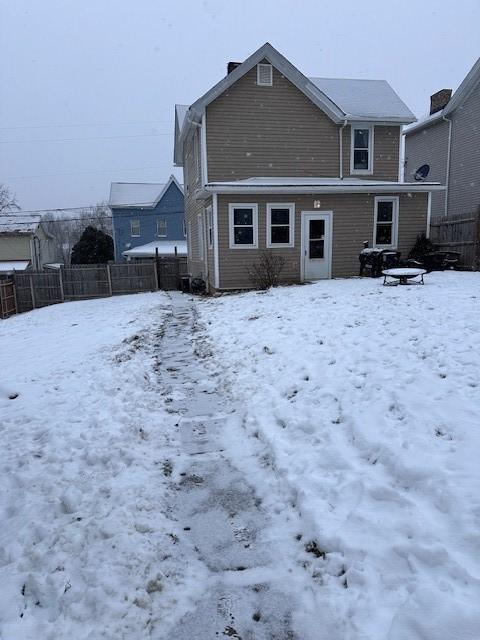 snow covered house featuring fence