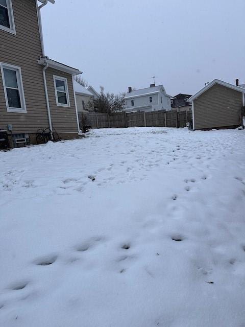 yard covered in snow with an outbuilding and fence