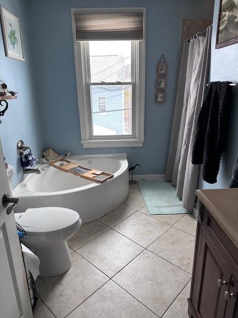 bathroom with a garden tub, toilet, a shower with shower curtain, tile patterned flooring, and vanity