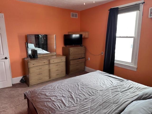 carpeted bedroom with visible vents and baseboards