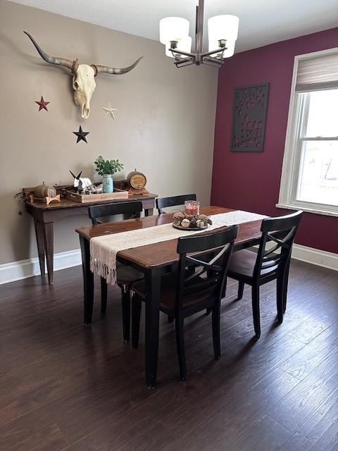 dining area with a chandelier, dark wood-style floors, and baseboards