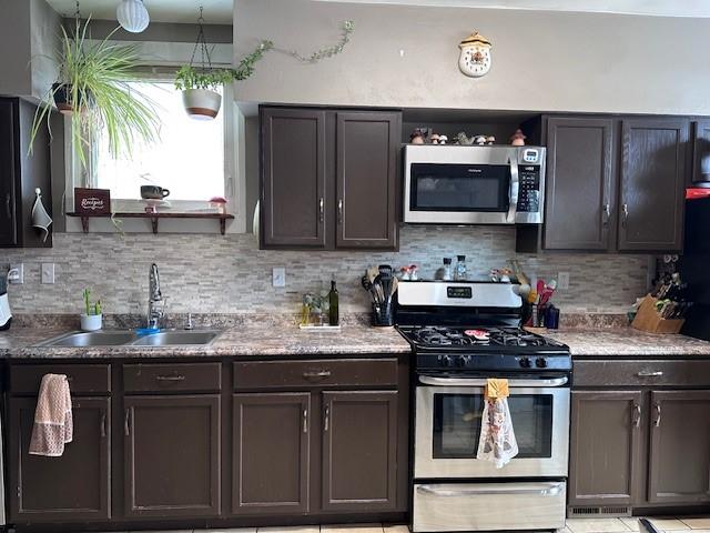 kitchen with a sink, light countertops, dark brown cabinets, appliances with stainless steel finishes, and backsplash