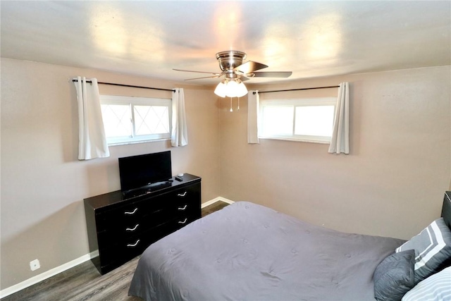 bedroom featuring multiple windows, ceiling fan, baseboards, and wood finished floors