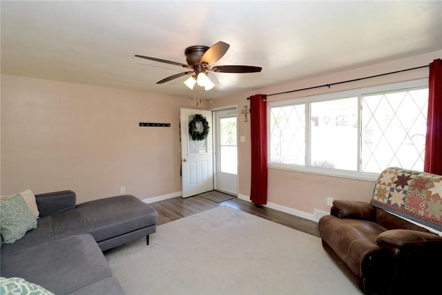 living area featuring baseboards, ceiling fan, and wood finished floors