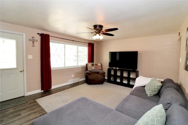 living area with visible vents, baseboards, wood finished floors, and a ceiling fan