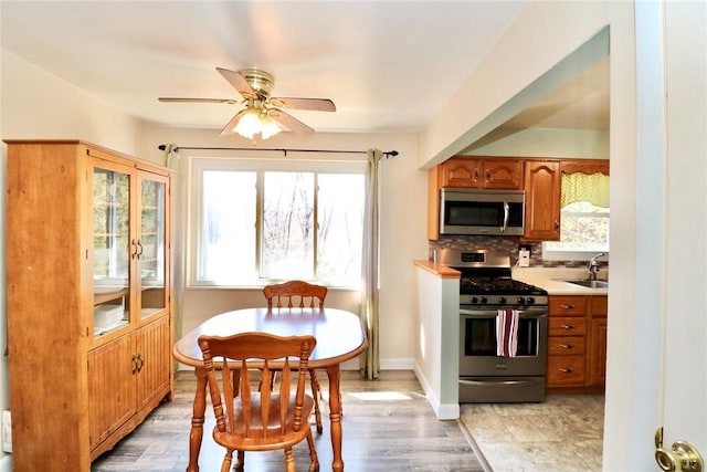 dining space featuring baseboards, ceiling fan, and light wood finished floors