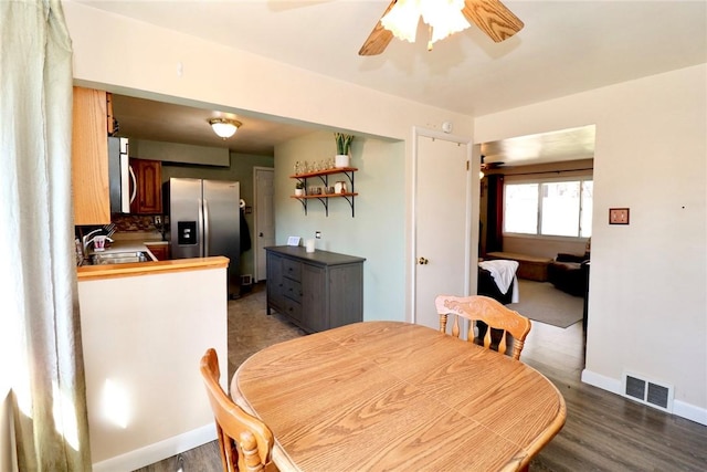 dining space with visible vents, baseboards, wood finished floors, and a ceiling fan