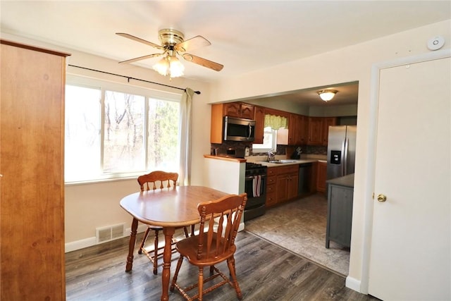 dining space featuring dark wood-style floors, a ceiling fan, visible vents, and baseboards