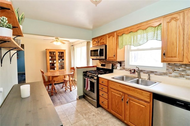 kitchen featuring a sink, backsplash, appliances with stainless steel finishes, and light countertops