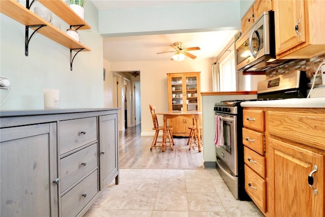 kitchen featuring open shelves, light tile patterned flooring, ceiling fan, light countertops, and appliances with stainless steel finishes