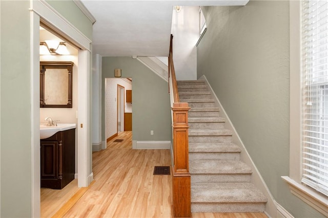 stairs featuring visible vents, baseboards, and wood finished floors