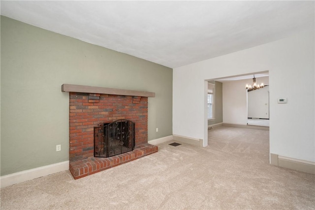 unfurnished living room featuring a chandelier, a brick fireplace, baseboards, and carpet