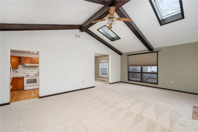 unfurnished living room featuring visible vents, light carpet, beam ceiling, a ceiling fan, and a skylight