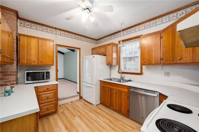 kitchen with a sink, appliances with stainless steel finishes, brown cabinetry, and light countertops