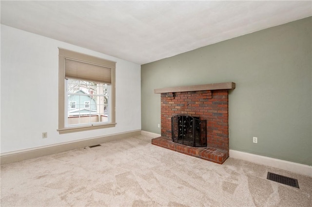 unfurnished living room with a brick fireplace, carpet flooring, and visible vents