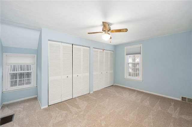 unfurnished bedroom featuring baseboards, visible vents, two closets, and carpet