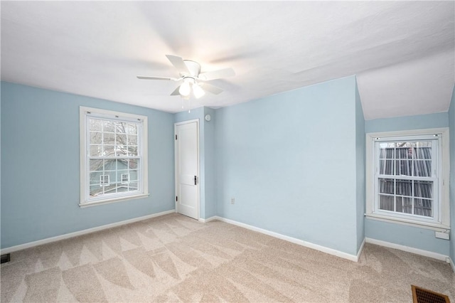 unfurnished room featuring ceiling fan, light colored carpet, visible vents, and baseboards