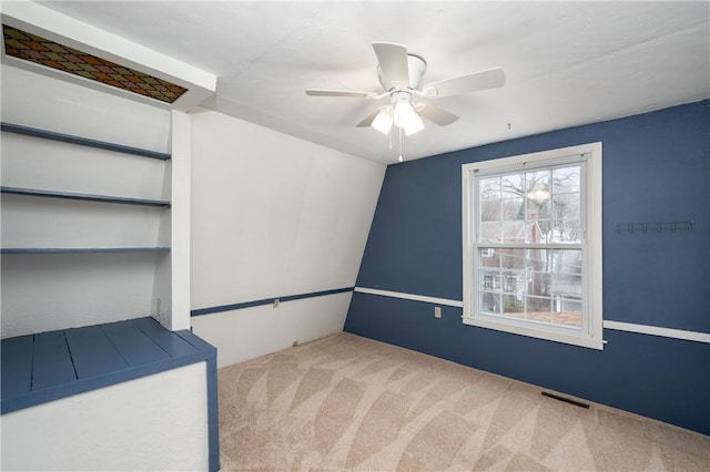 carpeted spare room featuring visible vents and a ceiling fan