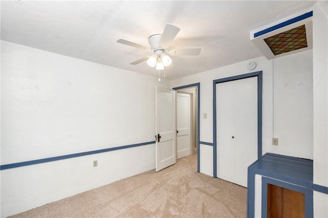 unfurnished bedroom featuring a closet, light colored carpet, and a ceiling fan