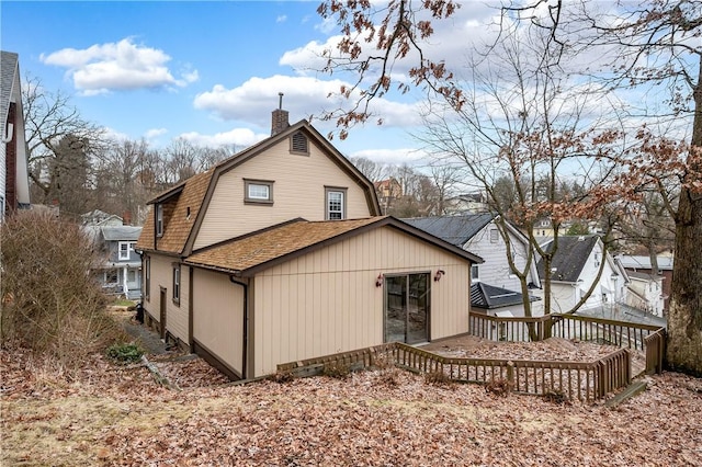 rear view of property featuring a gambrel roof and a chimney