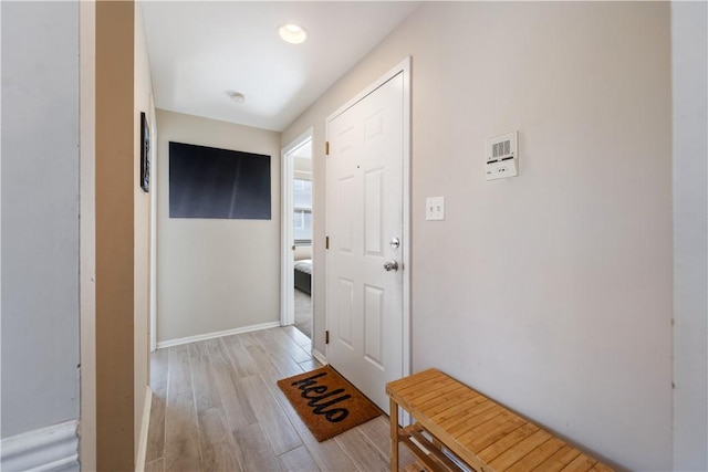 doorway featuring baseboards and light wood-type flooring