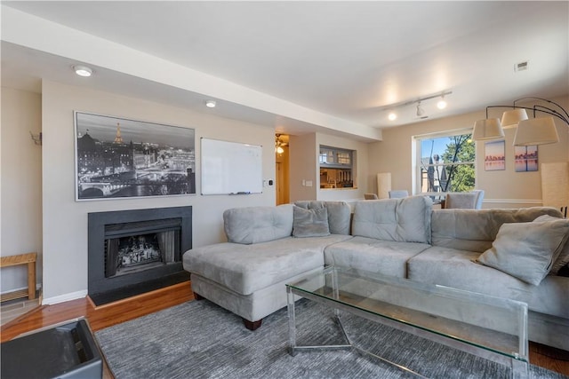 living area featuring wood finished floors, visible vents, baseboards, a fireplace with flush hearth, and track lighting