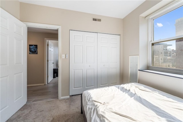 carpeted bedroom featuring visible vents, a closet, and baseboards