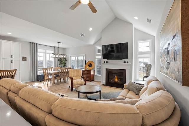 living room featuring light wood finished floors, visible vents, high vaulted ceiling, and ceiling fan